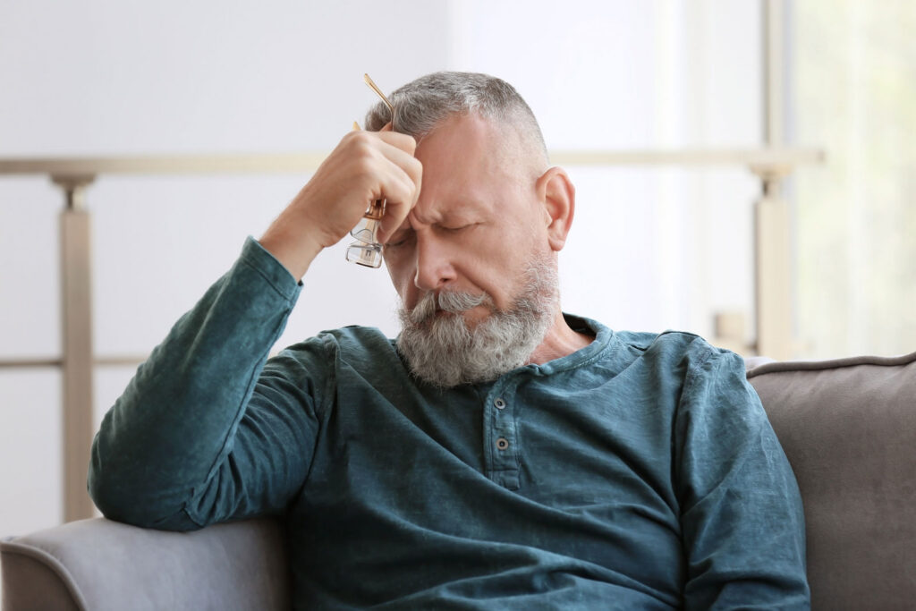Depressed senior man sitting in armchair indoors
