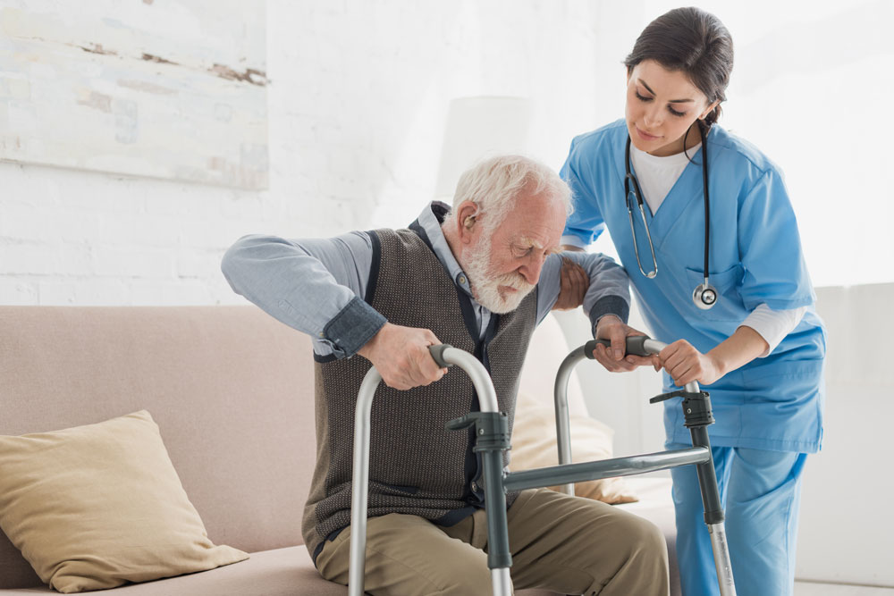 A nurse helping an elderly man stand up