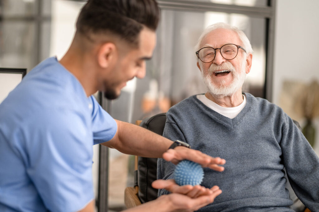 A male nurse helping an elderly man with hand exercises