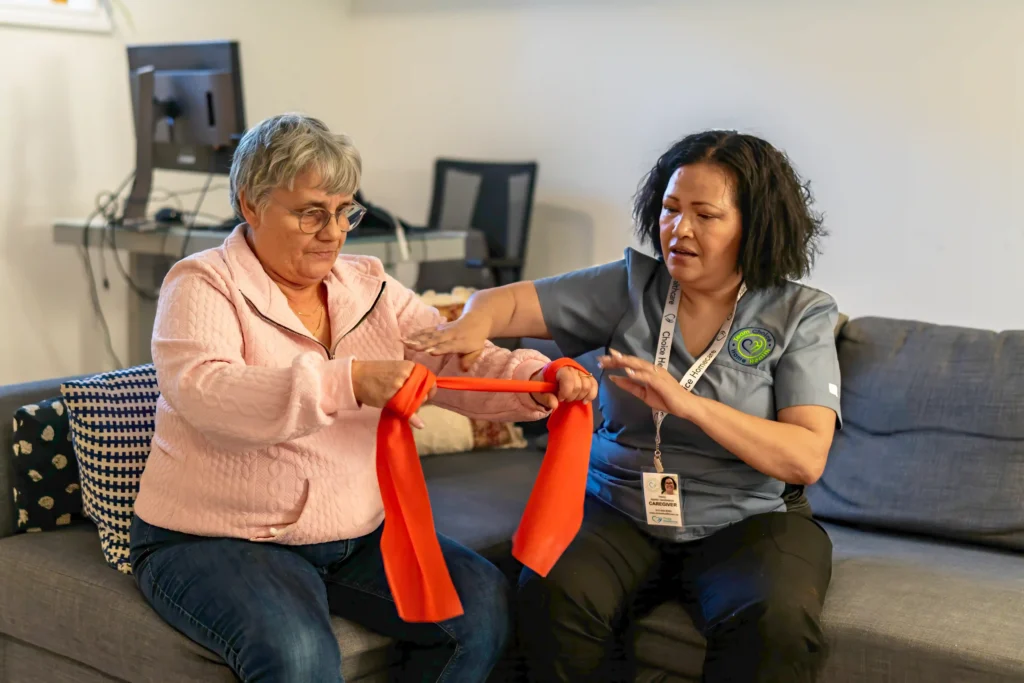 A nurse helping an elderly woman with hand exercises