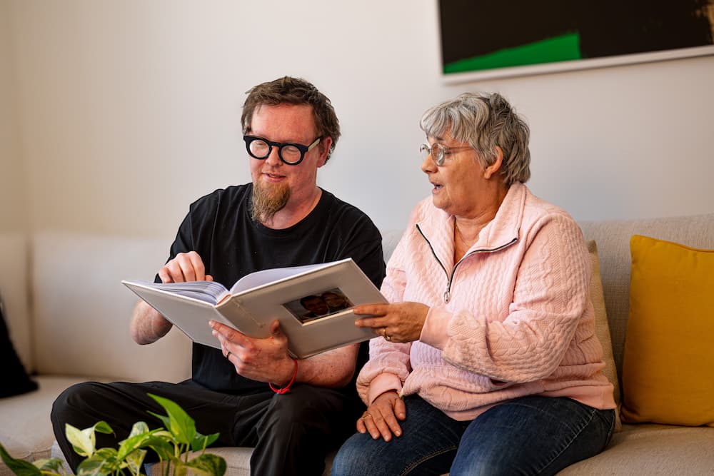 An elderly woman looking through a photobook with her son