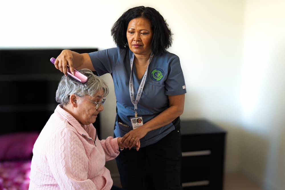 Nurse brushing an elderly woman's hair